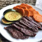 Grilled beef jerky, roasted sweet potatoes, and sautéed zucchini on a white plate, showcasing healthy and flavorful meal options from Waggy Chef kitchen.