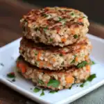Savory vegetable veggie patties, chickpeas, carrots, herbs, and spices, stacked on a white plate, perfect for healthy snacks or vegetarian meals.