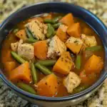 Cooked chicken and vegetable stew with sweet potatoes and green beans in a bowl, savory and hearty meal, healthy dinner option.