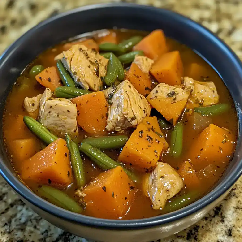 Cooked chicken and vegetable stew with sweet potatoes and green beans in a bowl, savory and hearty meal, healthy dinner option.
