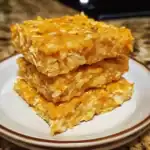 Golden oat-based dog treats stacked on a white plate, showcasing a healthy homemade snack option. Perfect for pet owners seeking nutritious, easy-to-make treats for their dogs.