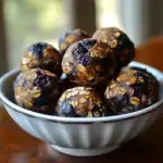Rich dark chocolate energy balls coated with oats in a white bowl on a rustic wooden surface, perfect healthy snacks or dessert options from Waggy Chef.