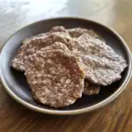 Crispy peanut butter dog treats on a black plate, healthy homemade snacks for dogs, Waggy Chef pet treats, natural dog treats with oats and peanut butter, dog-safe snacks for training or reward.