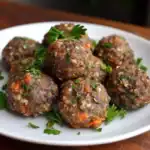 Savory homemade meatballs garnished with fresh parsley on a white plate, featuring a flavorful blend of herbs, spices, and vegetables for a delicious meal.