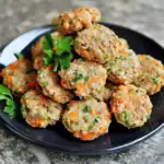 Crab cakes, seafood patties, mixed vegetables, crispy crab cakes with fresh herbs, delicious seafood appetizer on black plate.