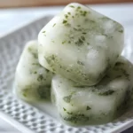 Herbal ice cubes with fresh herbs like parsley or cilantro, perfect for adding flavor to beverages and dishes.