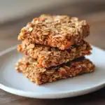 Oatmeal carrot energy bites stacked on a white plate, homemade healthy dog treats from Waggy Chef. Perfect for nutritious snacks, rich in oats and carrots for dogs' health and energy.