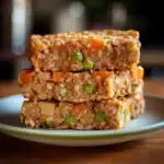 Delicious homemade veggie and meatloaf slices with peas, carrots, and potatoes, showcasing a hearty and nutritious meal perfect for dog treats or a balanced canine diet.