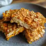 Oatmeal and carrot dog treats on a dark plate, close-up shot.