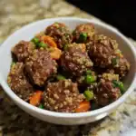 Crispy quinoa meatballs with vegetables served in a white bowl on a granite countertop, healthy pet treat, high-protein dog food, Waggy Chef pet cuisine, nutritious homemade dog meal.