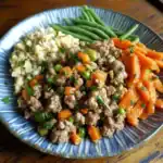 Ground-beef-stir-fry-with-carrots-green-beans-and-mashed-potatoes on blue ceramic plate.