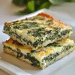 Baked spinach and cheese slice on white plate, healthy vegetable casserole, homemade savory snack, nutritious meal, Waggy Chef recipe, vegetarian dish with cheese and greens.