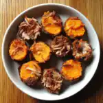 Juicy roasted sweet potatoes stuffed with tender pulled pork, perfect for healthy and hearty meals, served on a white plate with a wooden background.