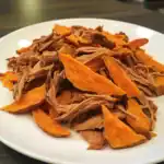 Shredded beef with roasted sweet potatoes served on a white plate, healthy pet food.