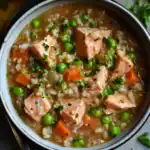Creamy salmon and vegetable barley soup with peas, carrots, and fresh herbs - hearty and healthy meal perfect for cozy dinners.