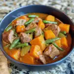 Beef stew with carrots and green beans, hearty homemade dog food recipe, Waggy Chef nutritious meal for dogs, wholesome dog stew in a black bowl, healthy dog food idea with vegetables and beef.