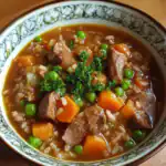 Savory beef and vegetable stew with carrots and green peas in a decorative bowl, garnished with parsley for a hearty Waggy Chef dish.