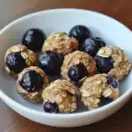 Healthy blueberry energy bites with oats and natural ingredients in a white bowl, perfect for snacks or breakfast, featuring fresh blueberries and oat topping.