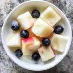 Fresh apple cubes with blueberries in a white bowl, healthy snack, vibrant fruits, dessert, summer fruit platter, colorful fruit presentation, nutritious fruit snack, fruit salad, healthy eating, fruit bowl, natural fruit ingredients.