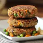 Delicious quinoa veggie burgers with colorful vegetables, crispy outside, served on a white plate, perfect for healthy vegetarian meals.