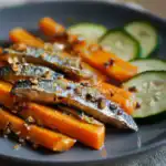 Fresh grilled mackerel with roasted carrots and cucumber slices on a dark plate, healthy seafood dish from Waggy Chef.