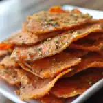 Crispy baked salmon skin chips garnished with herbs, perfect for healthy snacking and seafood lovers.