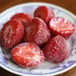 Juicy frozen strawberries on a decorative plate, showcasing fresh, vibrant red berries with icy frost for a healthy snack or dessert ingredient.