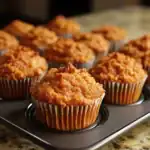 Freshly baked carrot muffins with a moist, crumbly texture in a muffin tin. Perfect for healthy snacking, breakfast, or brunch, these homemade muffins combine wholesome ingredients with a delicious flavor.