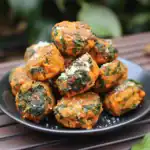 Crunchy spinach and sweet potato veggie balls with a hint of seasoning, served on a black plate. Perfect for healthy snacks or appetizers, combining fresh ingredients with delicious flavor. Excellent for vegan and vegetarian diets.
