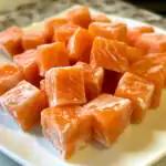 Fresh frozen salmon cubes for pet treats on a white plate, showcasing healthy dog treat options, sweet and nutritious seafood snacks, ideal for pet owners seeking high-quality ingredients.