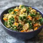 Quinoa salad with kale and diced carrots in a black bowl, healthy vegan superfood dish, nutritious meal option from Waggy Chef, gluten-free and plant-based recipe, vibrant and colorful food presentation.
