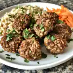 Savory meatballs with toasted oats and herbs, served with rice and shredded carrots on a white plate. Perfect for healthy, protein-rich meals and easy to prepare at home. Delicious and nutritious.