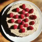 Fresh raspberry cake with creamy frosting and sliced almonds, perfect for dessert lovers seeking a delicious homemade treat.