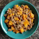 Minced beef with butternut squash, cooked to perfection, served in a vibrant green bowl. Healthy and flavorful meal, perfect for family dinner or meal prep. Fresh ingredients, delicious homemade comfort food.