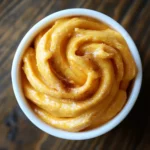 Creamy mashed sweet potatoes with a hint of cinnamon in a white bowl, served as a delicious side dish for any meal.