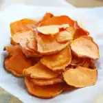 Sweet potato chips, crispy and golden, perfect for healthy snacks or side dishes. Freshly sliced sweet potatoes baked to perfection, showcasing vibrant orange color.