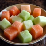 Frosted cantaloupe, honeydew, and watermelon cubes in a bowl, showcasing vibrant, fresh, and healthy fruit snack options for dogs.