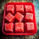 Juicy watermelon cubes in a red container, refreshing summer fruit snack.