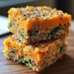 Roasted sweet potato bites topped with quinoa and spinach, garnished with spices, served on a wooden surface at Waggy Chef.