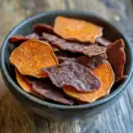 Crispy sweet potato chips in a black bowl for healthy dog treats and snacks.