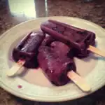 Refreshing homemade berry popsicles with a vibrant purple color and hints of fruit chunks, perfect for summer treats and healthy snacking.
