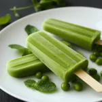 Fresh Green Celery Lime Popsicles on White Plate with Mint Leaves and Green Peas.