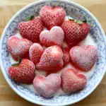 Fresh frozen strawberries shaped into hearts in a bowl for a romantic dessert or snack. Perfect for Valentine's Day, healthy treats, or strawberry lover gift ideas. Bright, sweet, and fruity.
