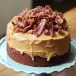 Creamy peanut butter frosting with crispy bacon topping on chocolate cake, delicious dessert for bacon and peanut butter lovers, perfect for special occasions and celebrations.