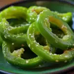 Fresh green pepper slices seasoned with salt and sesame seeds, close-up image showcasing vibrant color and texture, perfect for healthy snacking or cooking ingredients.