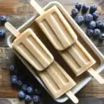 Creamy blueberry popsicles on wooden surface with fresh blueberries, refreshing summer treat, homemade frozen dessert, healthy snack option, Waggy Chef.