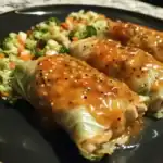Roasted cabbage rolls with savory sauce and fresh vegetable side dish on black plate, healthy homemade meal, channeling Waggy Chef's nutritious recipe ideas.