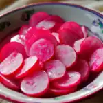Radish slices in a colorful bowl, fresh and vibrant radish, healthy vegetable snack, prepared for eating or cooking, close-up, bright natural lighting, traditional dish, vegetarian ingredient, farm-fresh radish, nutritious vegetable, Asian cuisine ingredient, crunchy snack, salad topping, aesthetic food presentation, organic produce, healthy eating, vegetable platter, summer salad, vegan ingredients, farm-to-table, culinary ingredient.