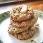 Chewy oatmeal cookies with chunks of white chocolate on a decorative plate. Soft, golden-brown, and homemade, perfect for snack or dessert.