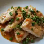 Pan-seared fish fillets with quinoa, peas, and diced vegetables, garnished with fresh herbs, served on a white plate for a healthy, protein-rich meal.
